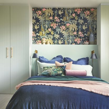 Sage green bedroom with sage wardrobes and floral wallpaper behind the bed