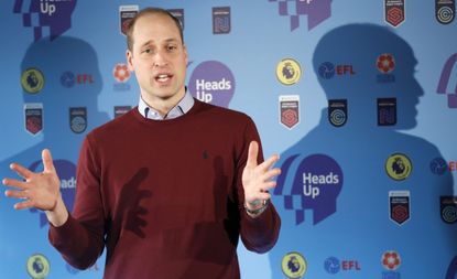 Prince William speaking in front of a backdrop covered in logos