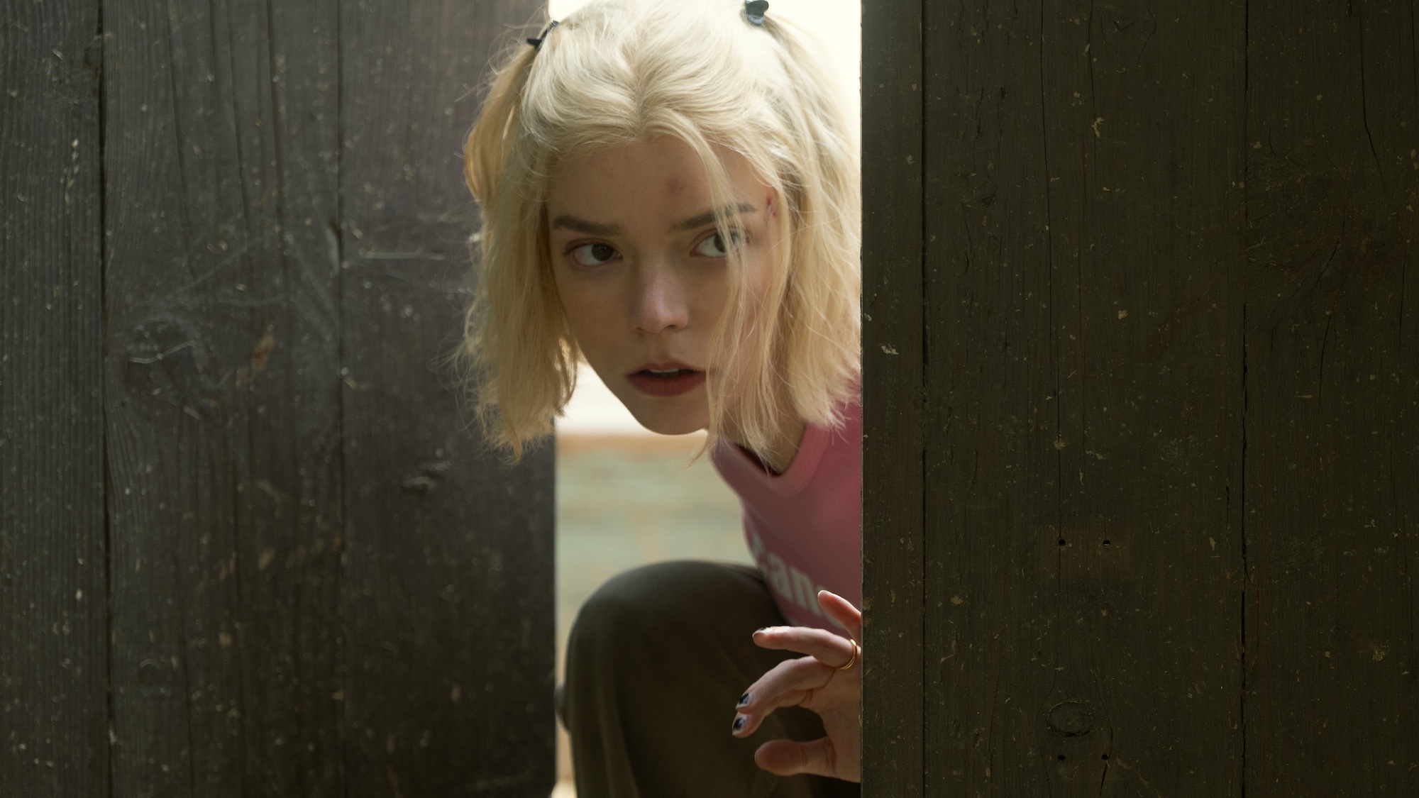 Anya Taylor-Joy sneaking through a wood door in "Lucky," now streaming on Apple TV.