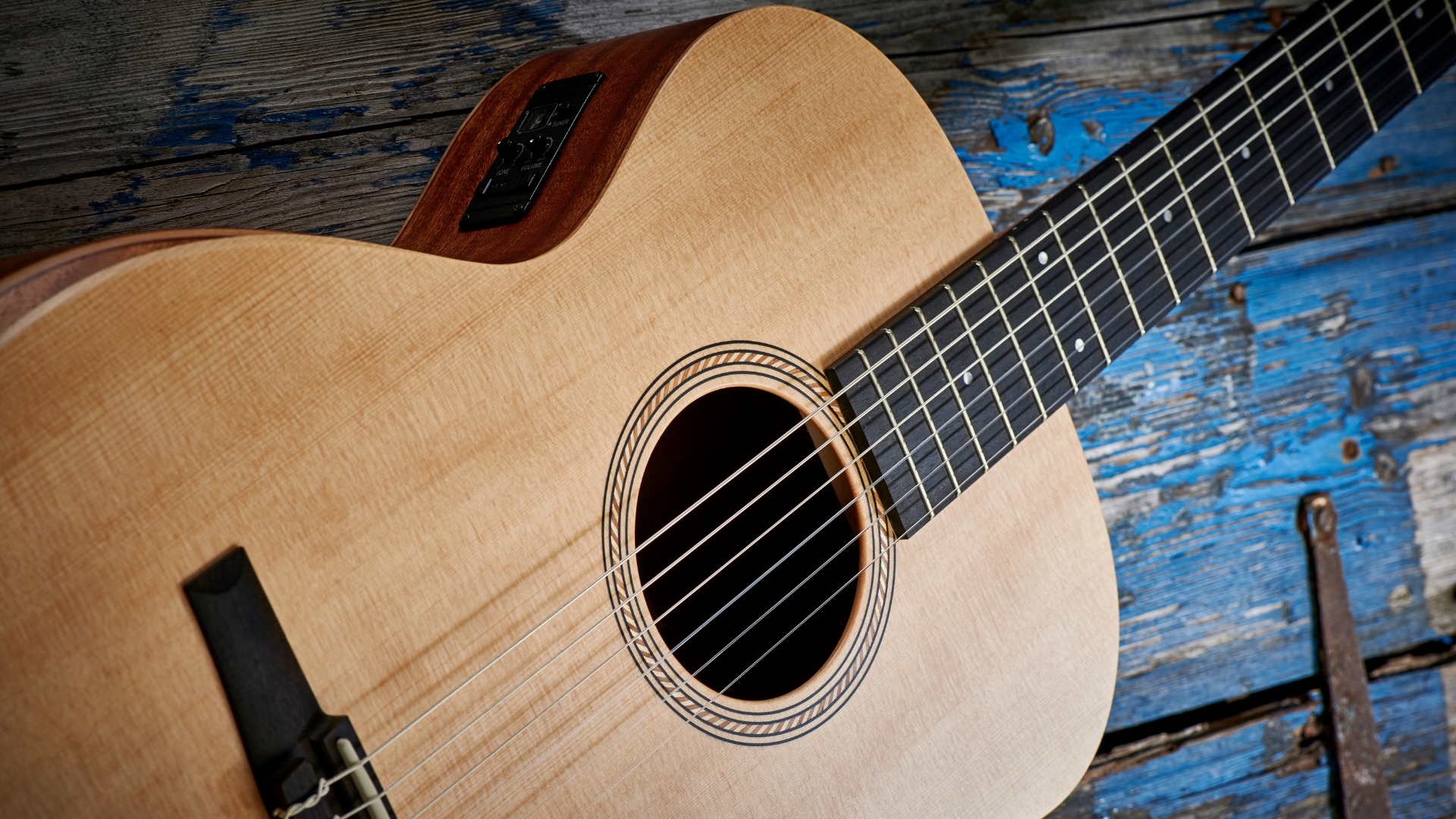 A Taylor Academy 12 acoustic guitar on a wooden floor