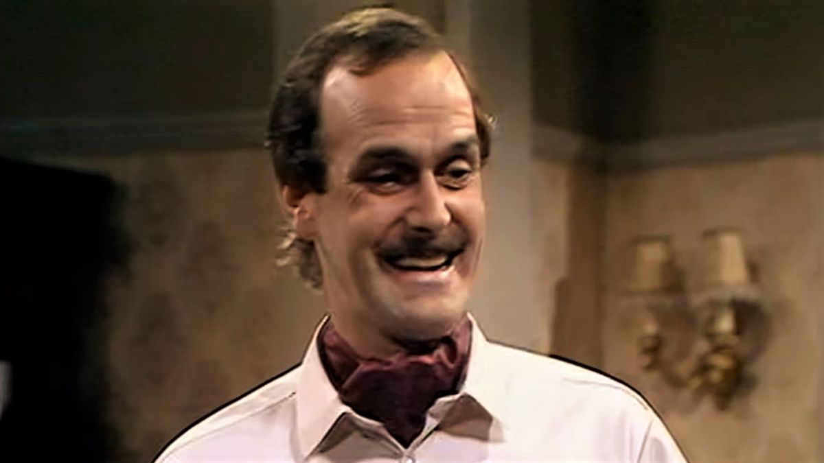 Basil Fawlty smiling in hotel restaurant in Fawlty Towers