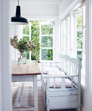 Rustic dining table and bench in a white wood panelled cabin