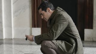 Ramón Rodríguez as Will Trent bending down looking at evidence