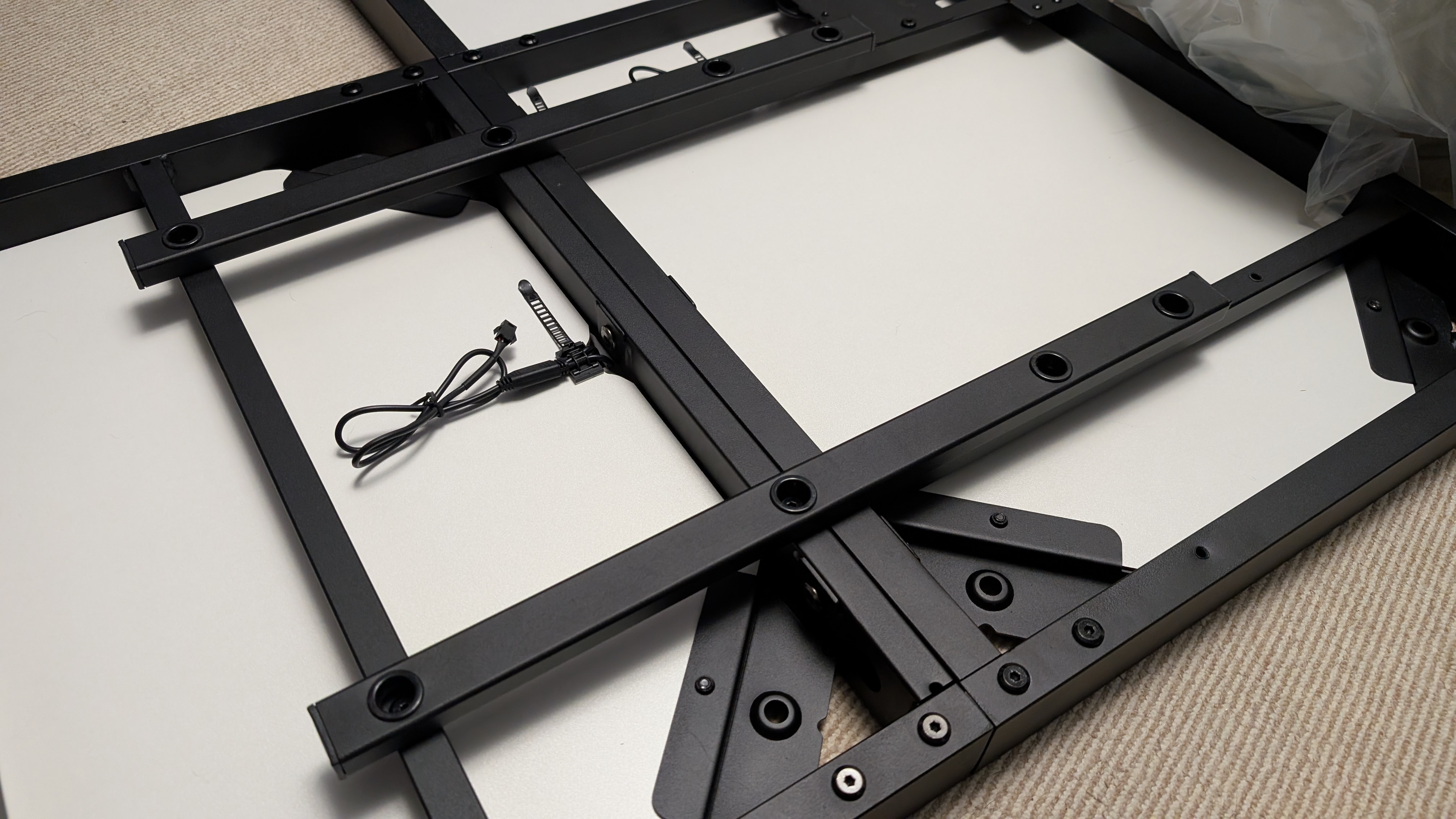 The underside of the Eureka Ergonomic GTG Wave gaming desk midway through assembly, showing the steel frame and bottom of the glass panel.