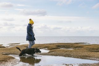 Woman talking her dog on the coast