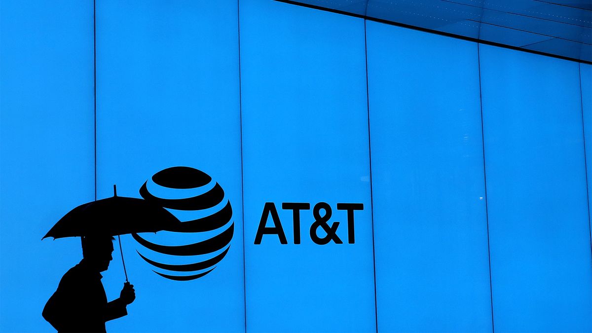 A man walks with an umbrella outside of AT&amp;T corporate headquarters on March 13, 2020 in Dallas, Texas.