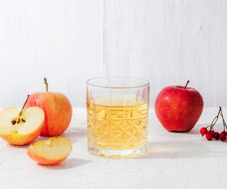 A glass of apple juice against a white background.