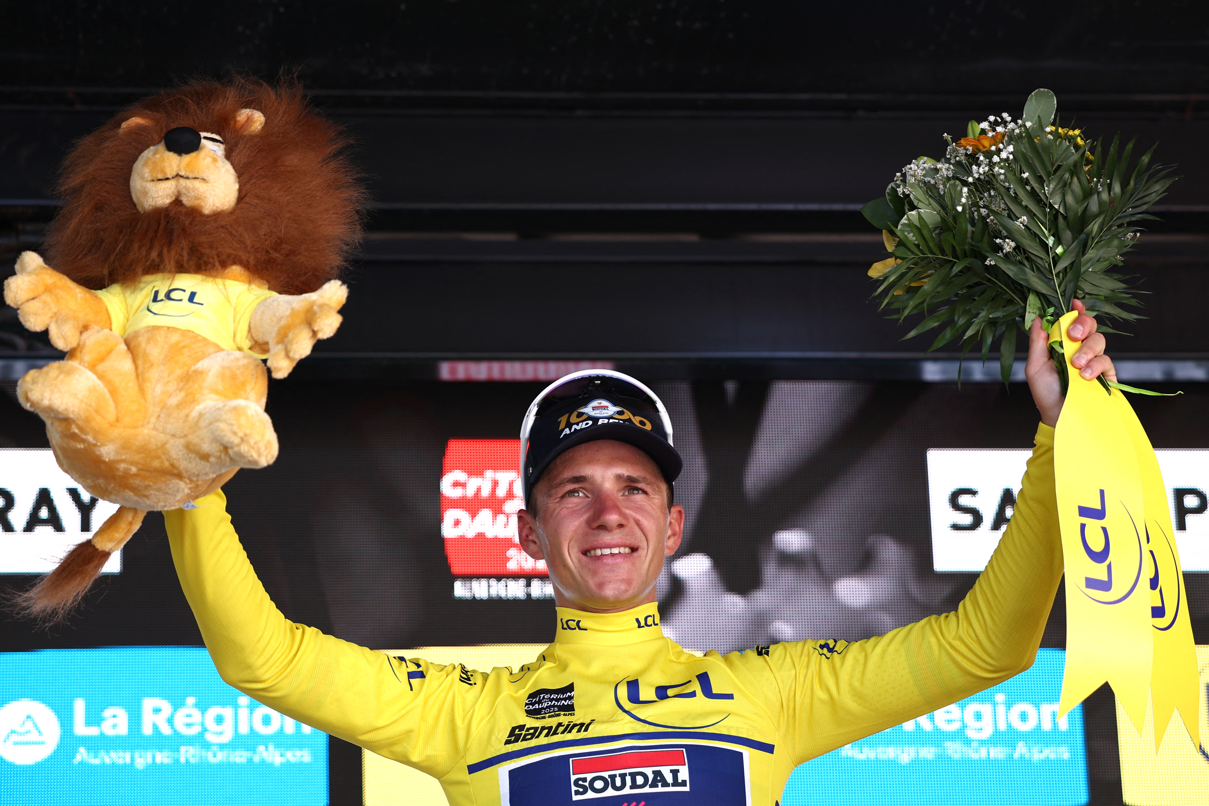 Soudal Quick-Step's Belgian rider Remco Evenepoel celebrates wearing the overall leader's yellow jersey after winning the stage on the podium of the 4th stage of the 77th edition of the Criterium du Dauphine cycling race, a 17,4 km individual time trial between Charmes-sur-Rhône and Saint-Péray, on June 11, 2025. (Photo by Anne-Christine POUJOULAT / AFP) (Photo by ANNE-CHRISTINE POUJOULAT/AFP via Getty Images)