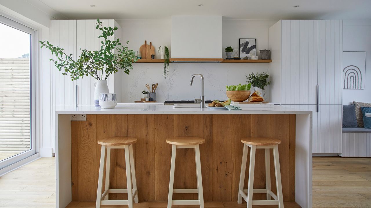 Kitchen with white cabinets, island with sink and wooden panneling