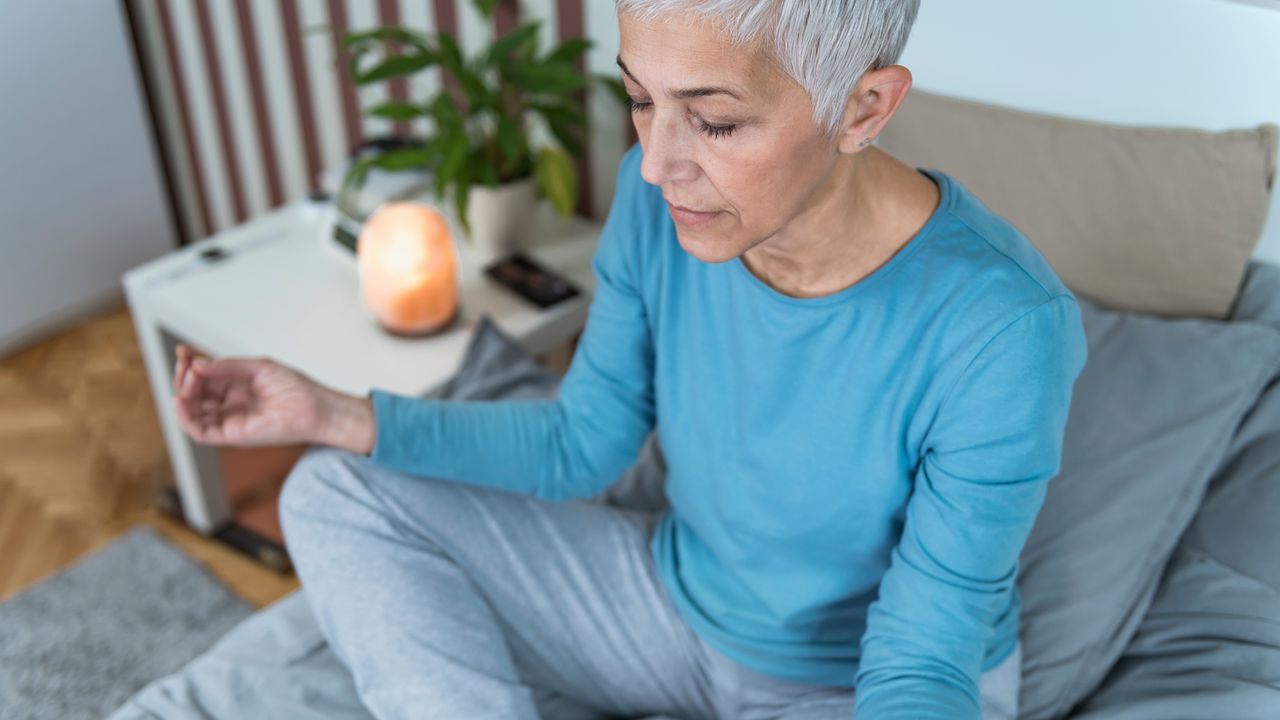 Woman practices mindfulness with a candle burning beside her