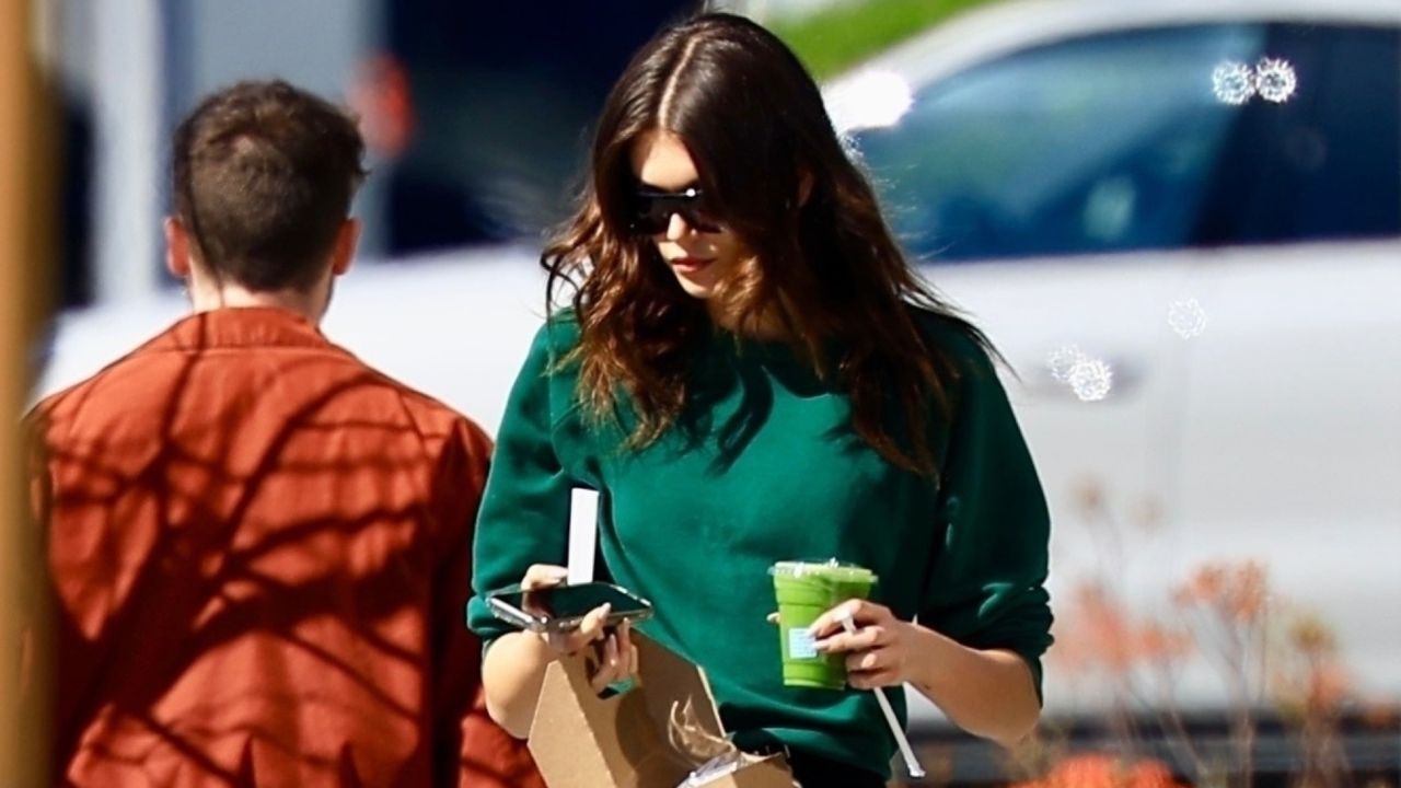 Kaia Gerber walks in Los Angeles wearing a green cropped sweater and wearing a pair of leggings