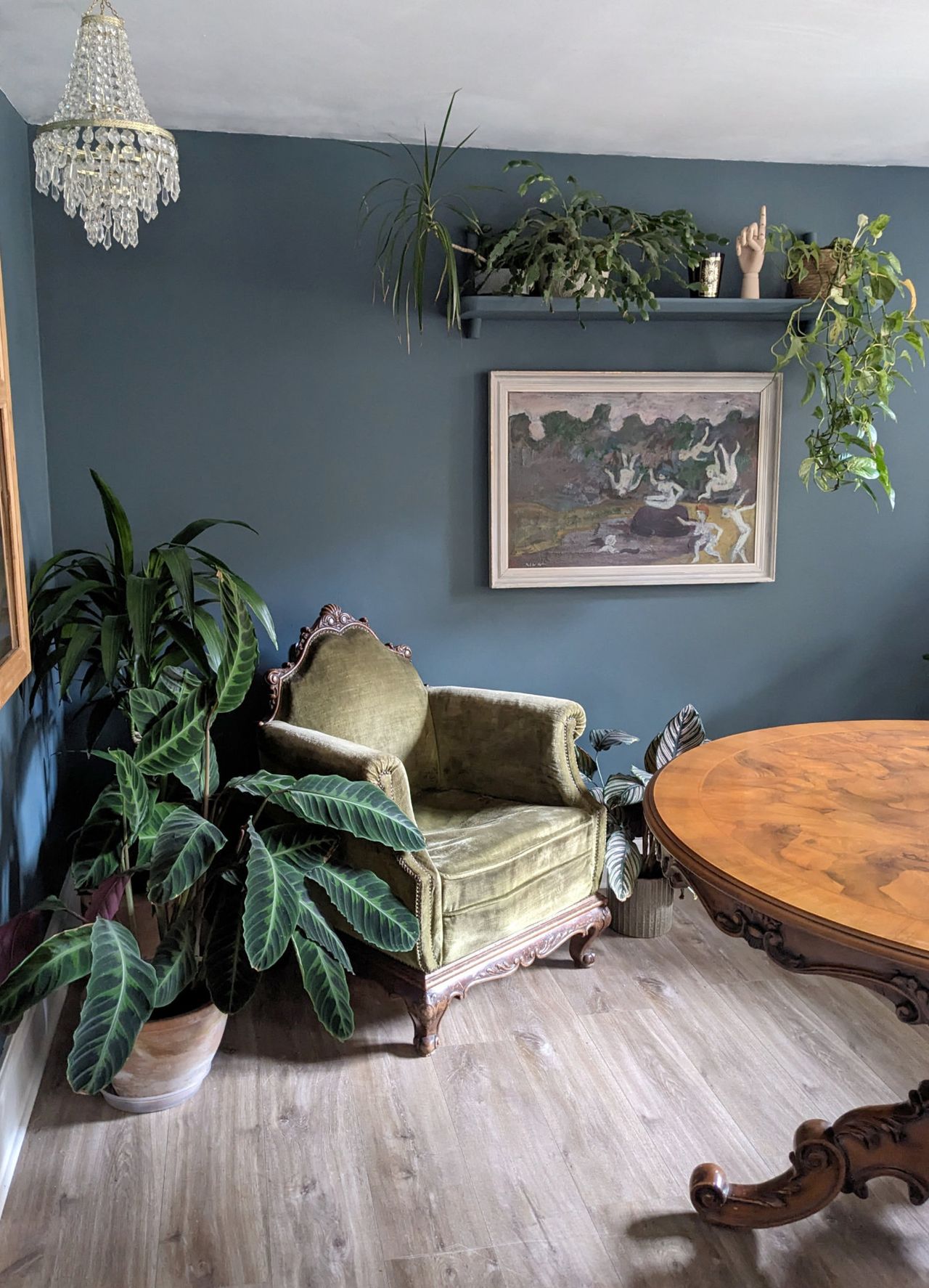 A room with blue walls and a velvet armchair surrounded by houseplants
