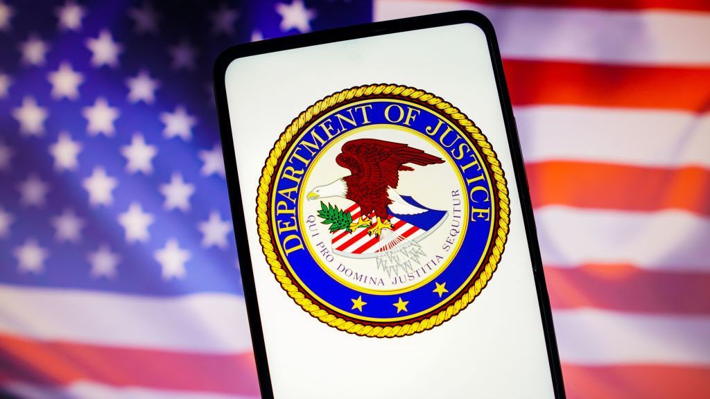 The DoJ logo on a smartphone with the US flag in the background