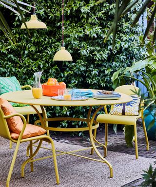 Garden decorating ideas showing a bright yellow table and chairs with colorful cushions
