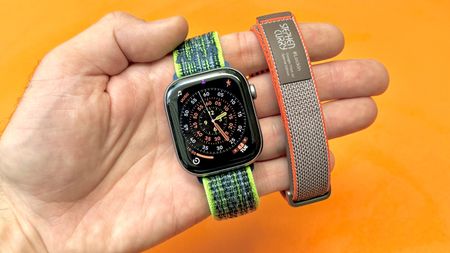 Close-up of the Apple Watch Series 11 next to the Fitbit Air; both are on colorful straps