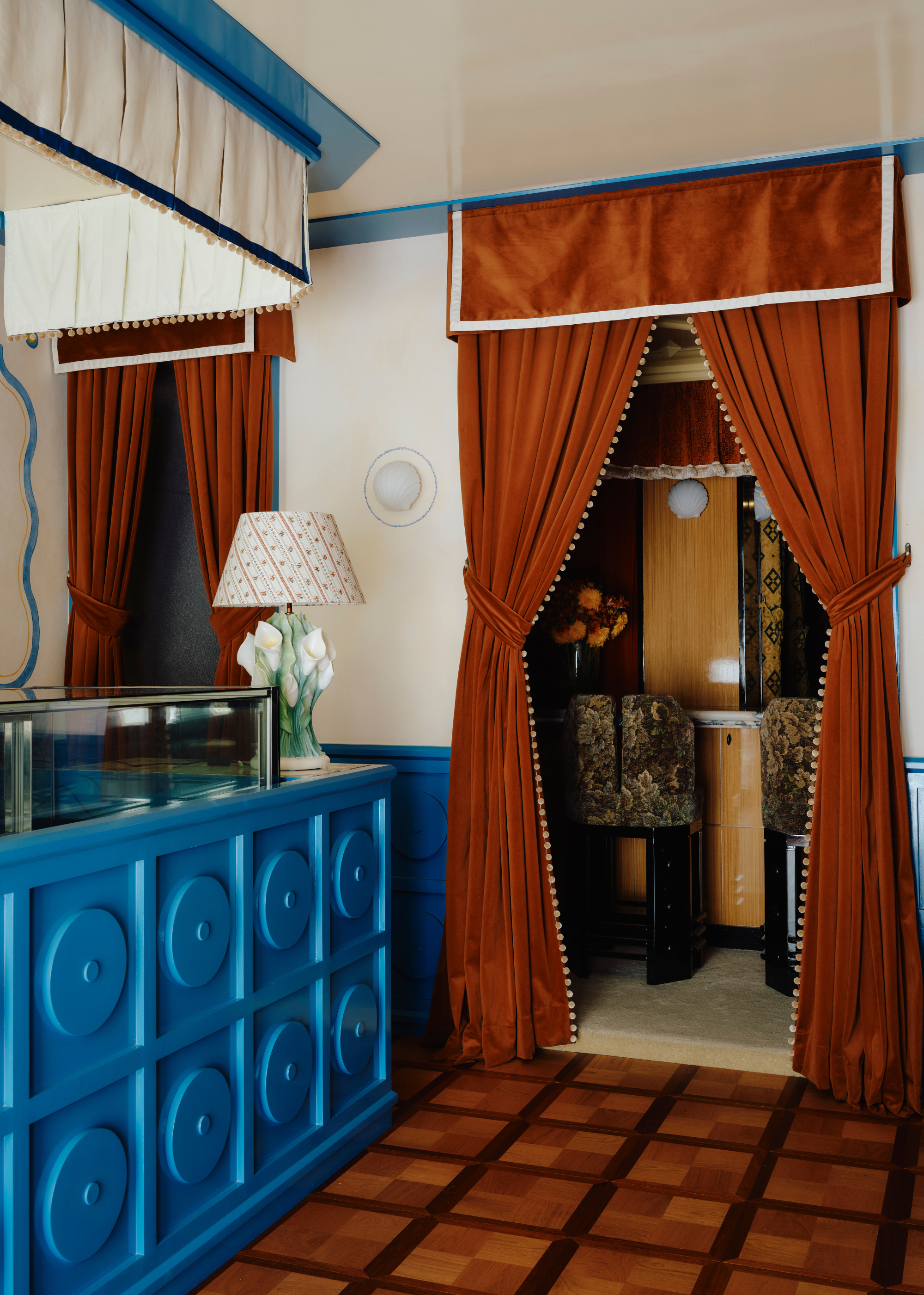 cafe with orange draped curtains, blue panelled walls and tiled floors