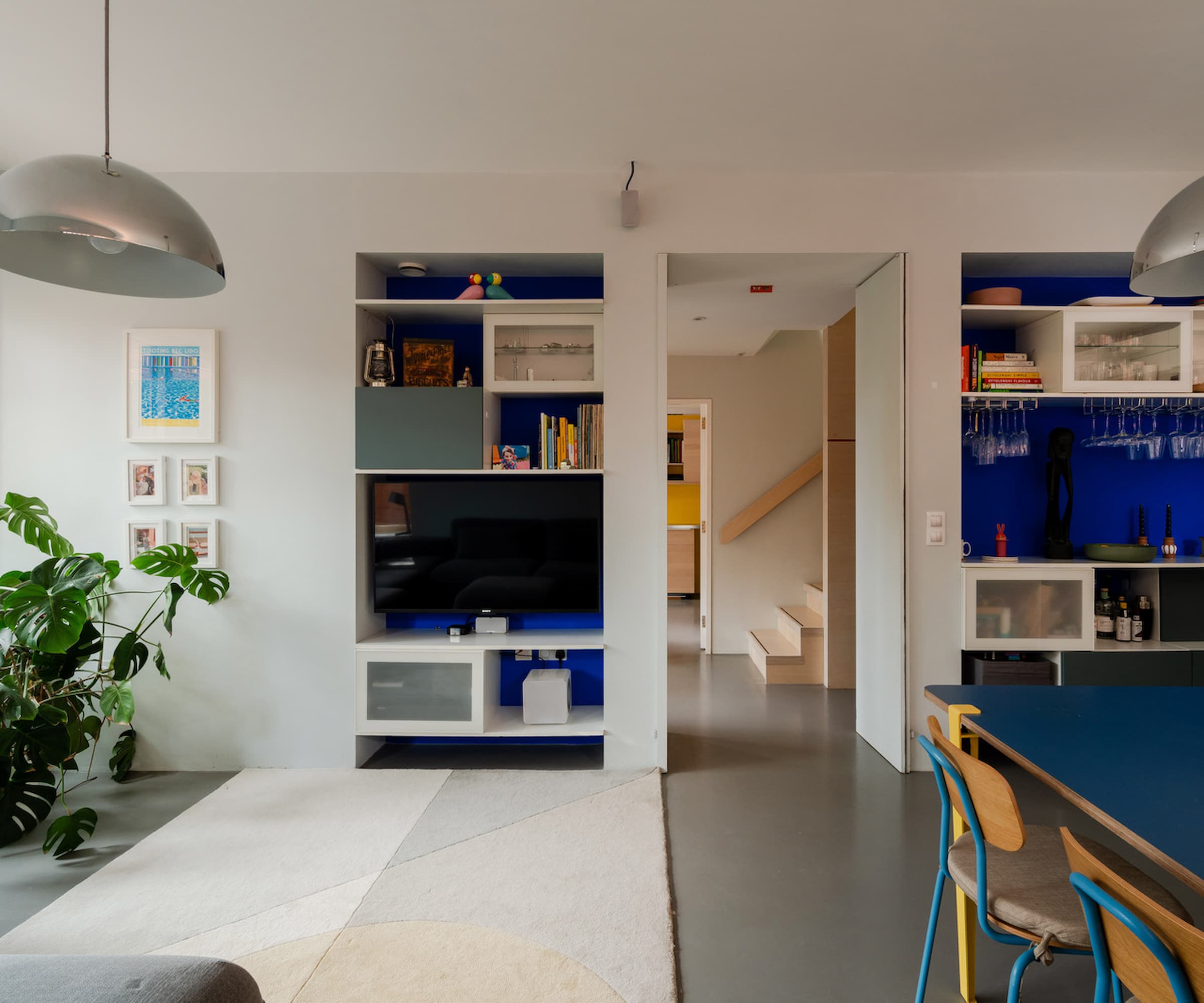 A hallway with a table in a sitting room leading to a wooden staircase