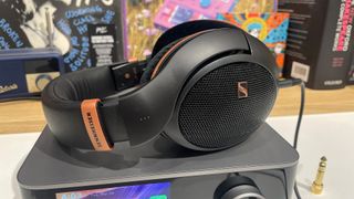 Sennheiser HD 505 open-back headphones sitting on music streamer in front of busy bookshelf