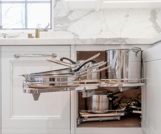A white kitchen corner cabinet with a pull out organizer