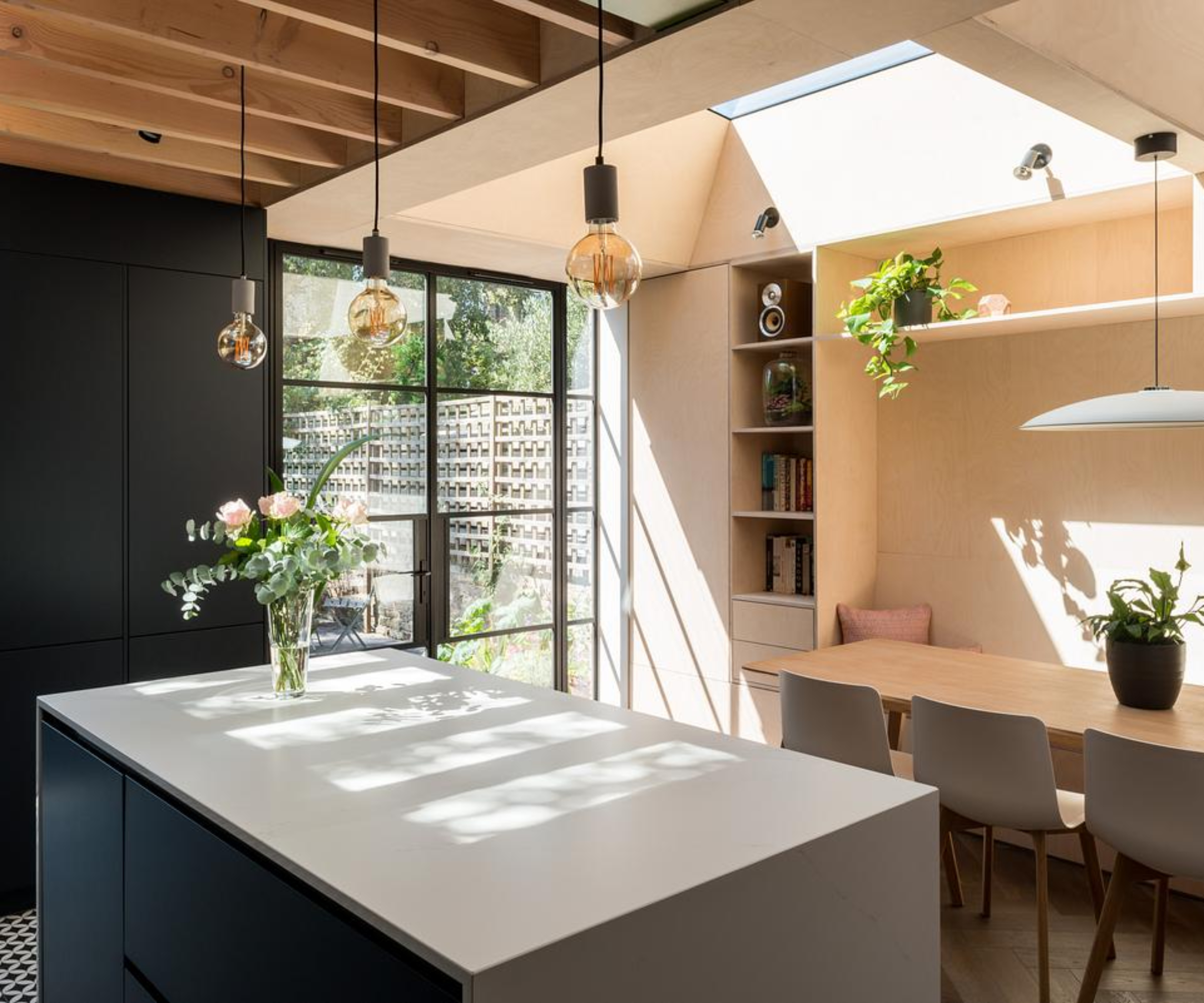 inside modern kitchen extension with beamed roof on one side and glazed rooflight on the other