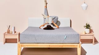 Siena Sleep memory foam mattress, featuring a person lying upside on the bed, with legs up the wall, reading a book