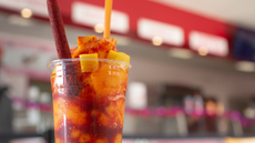 A view of a drink made of chamoy and mango, in a restaurant interior setting