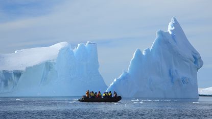 Iceberg and boat of humans