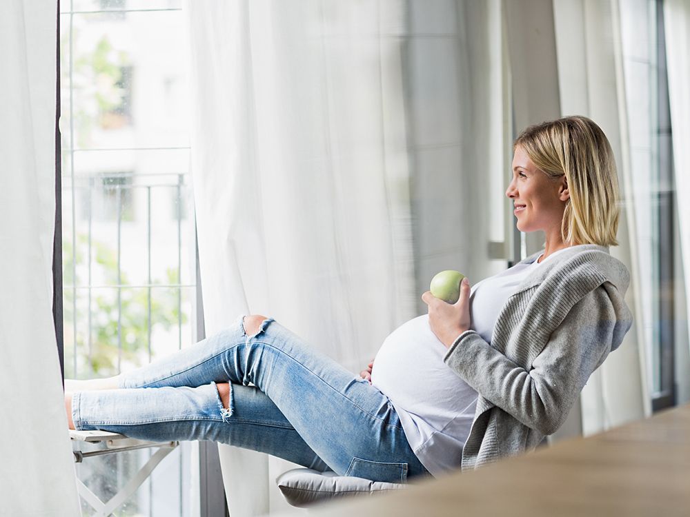 Full term pregnancy young woman eating apple