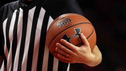 A referee holds an Under Armour basketball