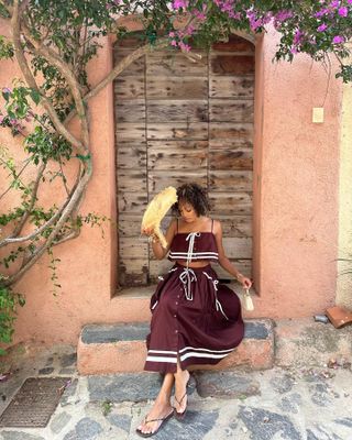 Woman wearing a burgundy outfit, straw hat, and flip flops