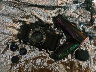 Camera with smoke grenades on sequined cloth