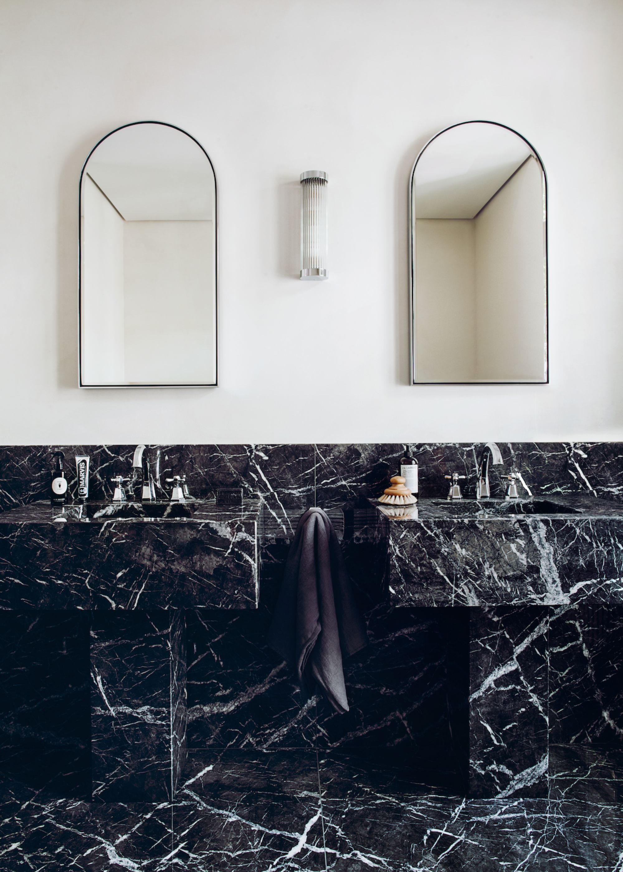 A bathroom with black, heavily veined flooring and basin