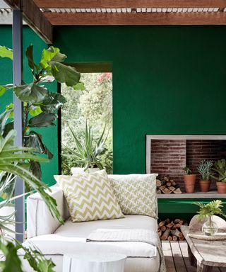 A fresh white sofa on a wooden deck by a green wall