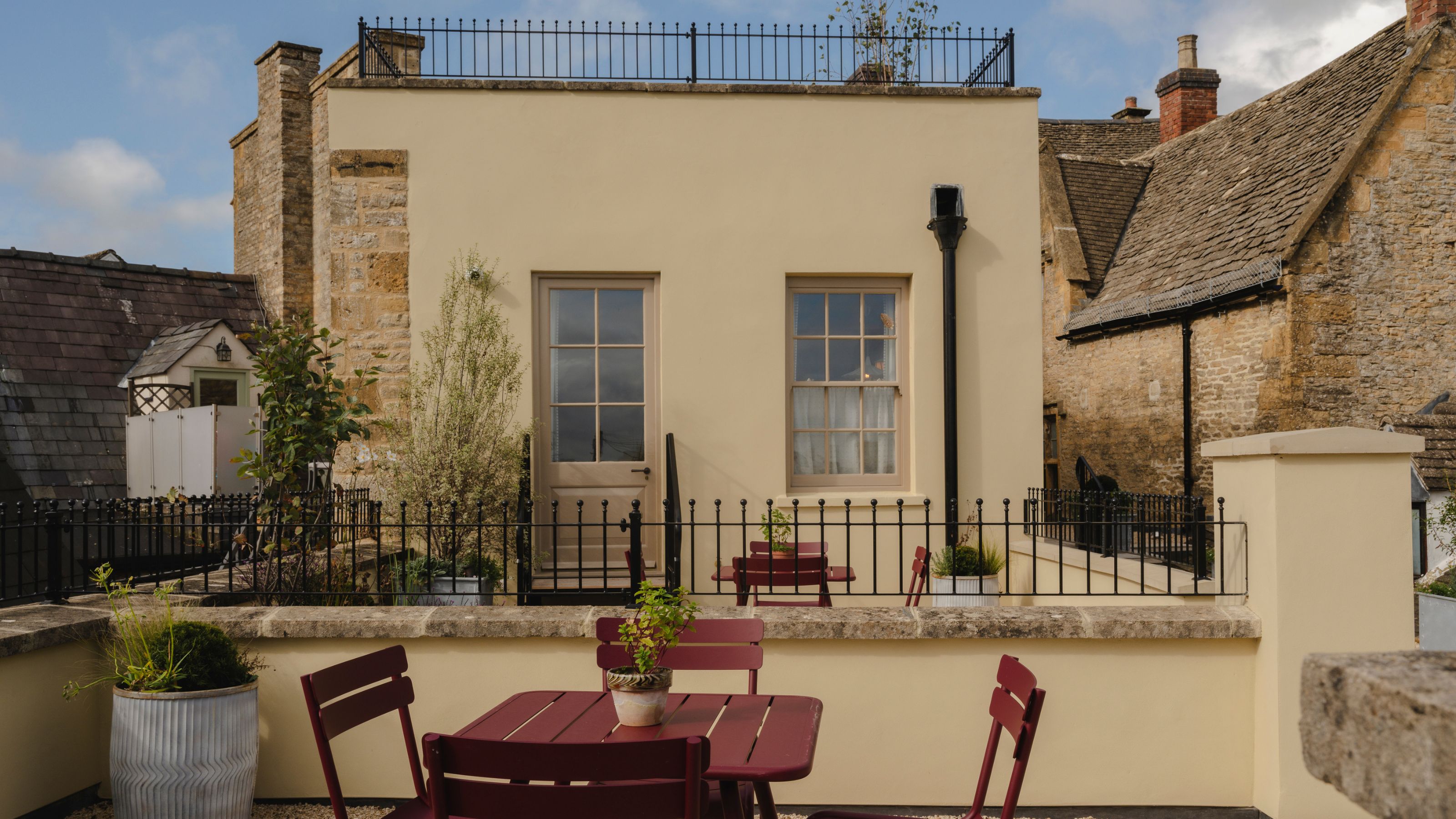 a soft cream yellow painted rooftop building in the cotswolds surrounded by cotswolds cottages