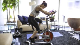 Should you buy an exercise bike? Image shows woman on exercise bike at home