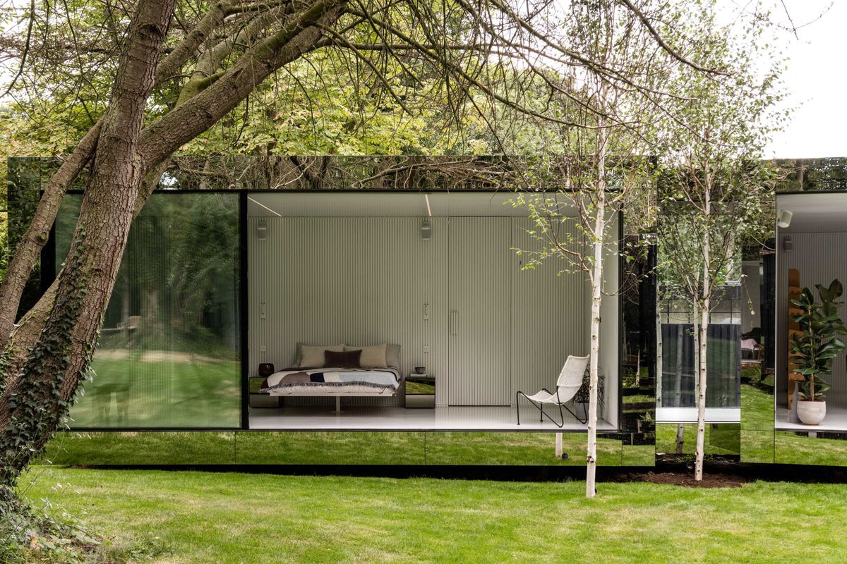A view from the garden looking into the bedroom shows a floating bed through three bifold windows