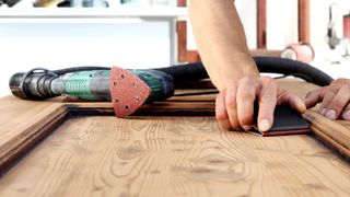 Hands manually sanding a finish on a wooden door