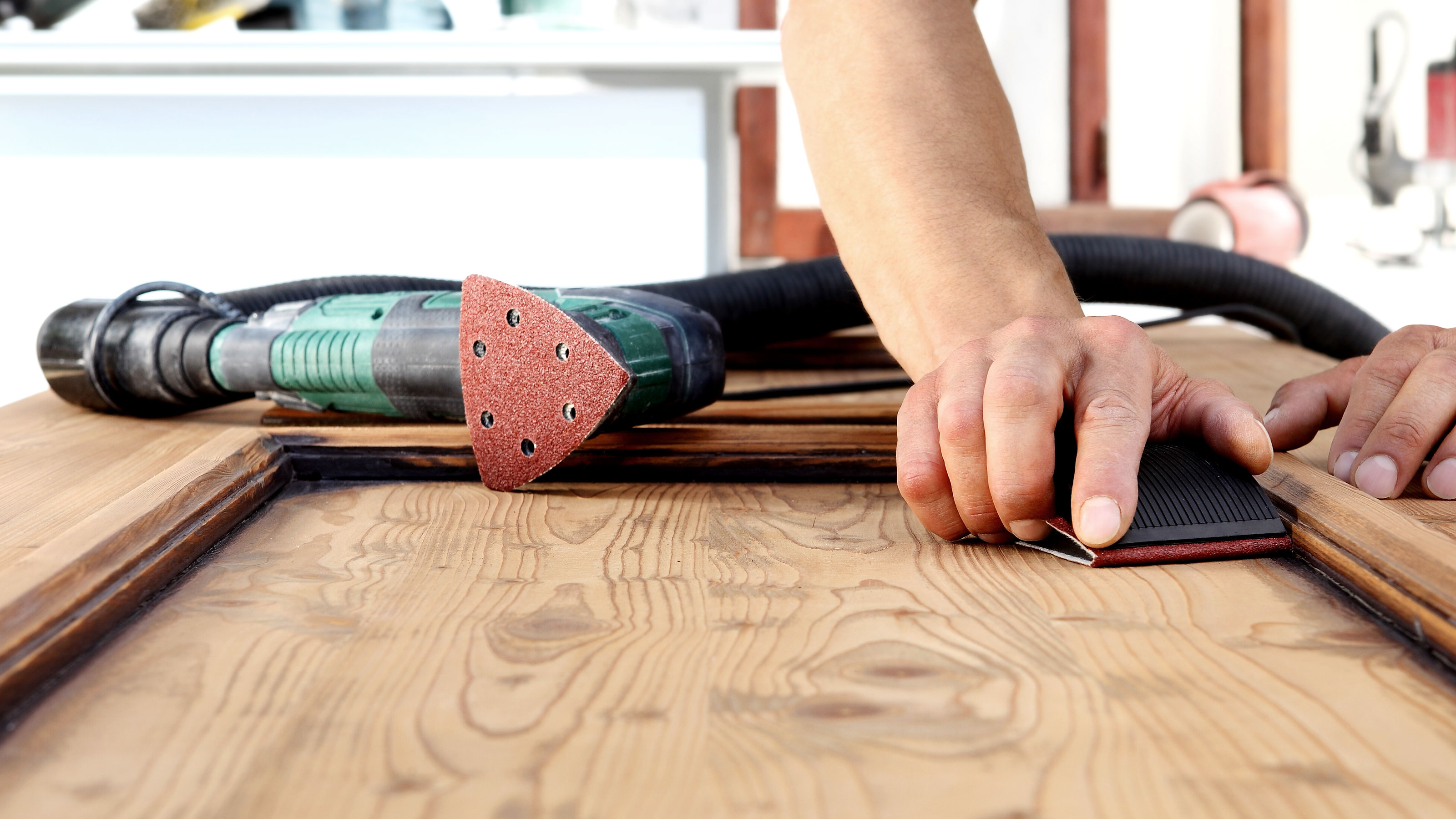 Hände schleifen manuell die Oberfläche einer Holztür ab