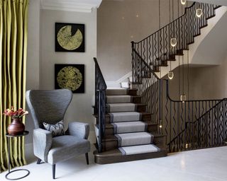 Staircase lighting ideas by Rebecca Hughes Interiors with suspended lights and green chair