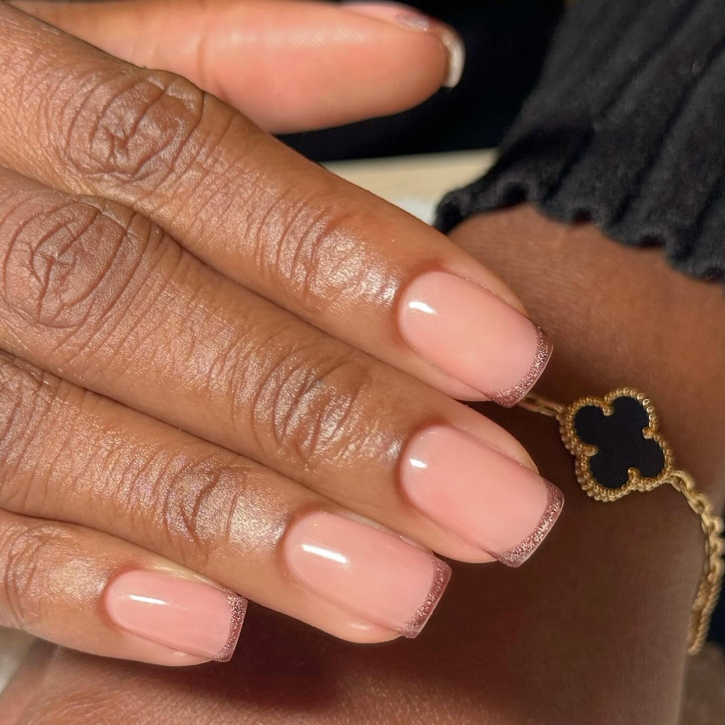 A short, square, brown, cat-eye French tip manicure