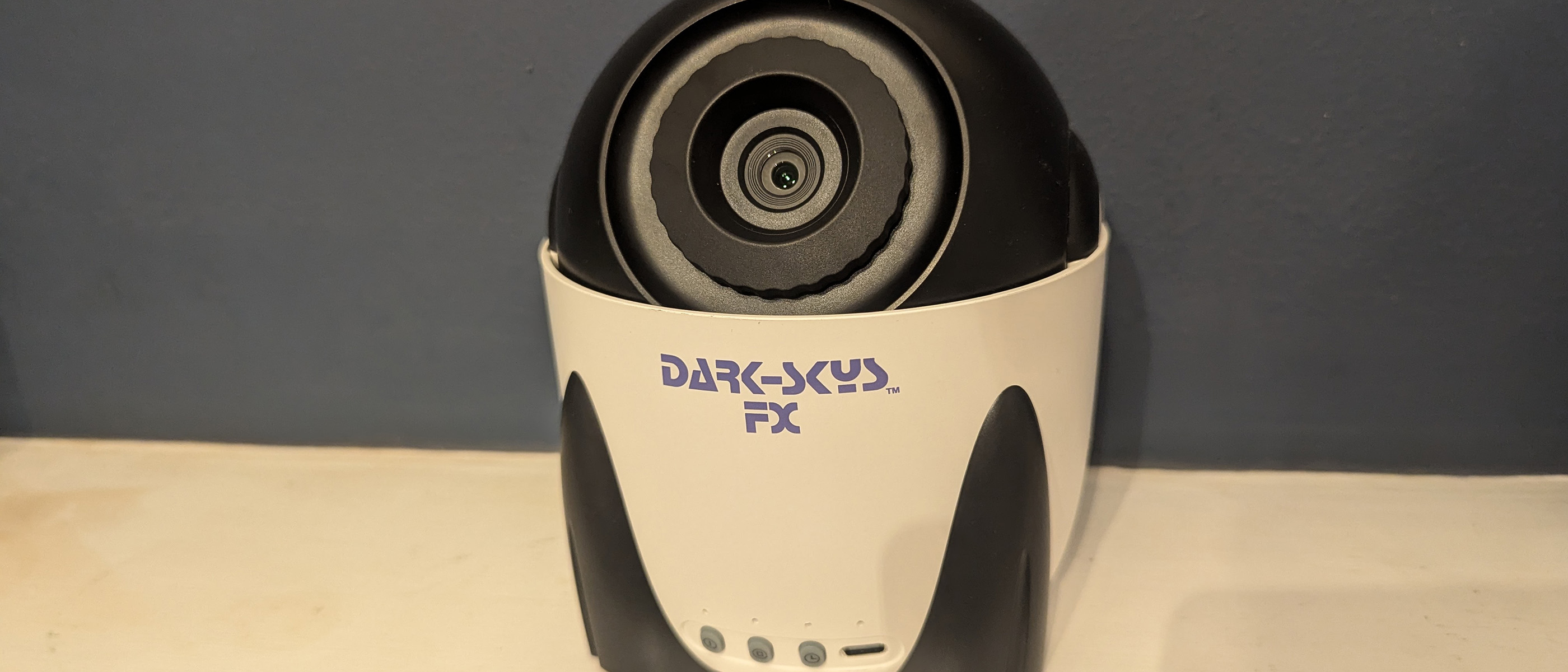 Dark Skys DS-FX Star Projector on a white shelf in front of a blue wall