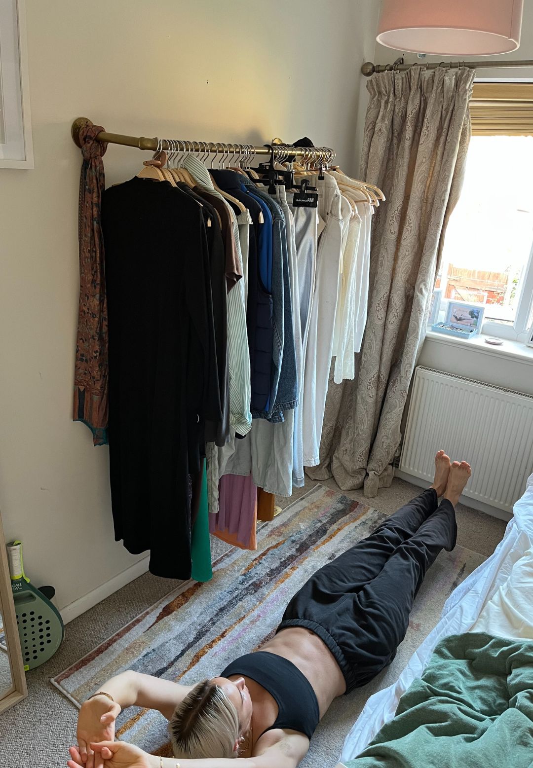 A woman practices a Pilates hollow hold on her bedroom floor