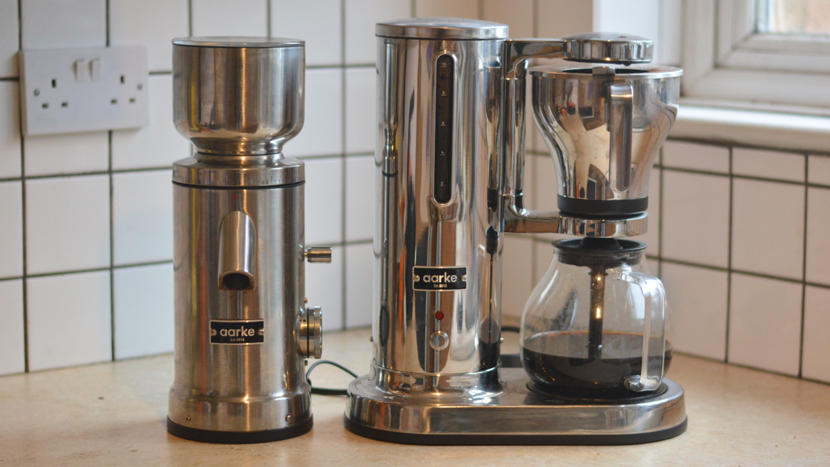 Image of the Aarke Coffee System &ndash; a stainless steel coffee bean grinder and drip coffee maker &ndash; positioned on a kitchen counter