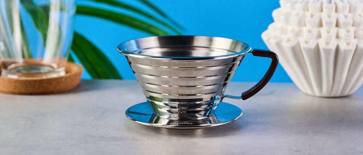 kalita wave stainless steel pour-over coffee dripper photographed against a blue background with kalita filters