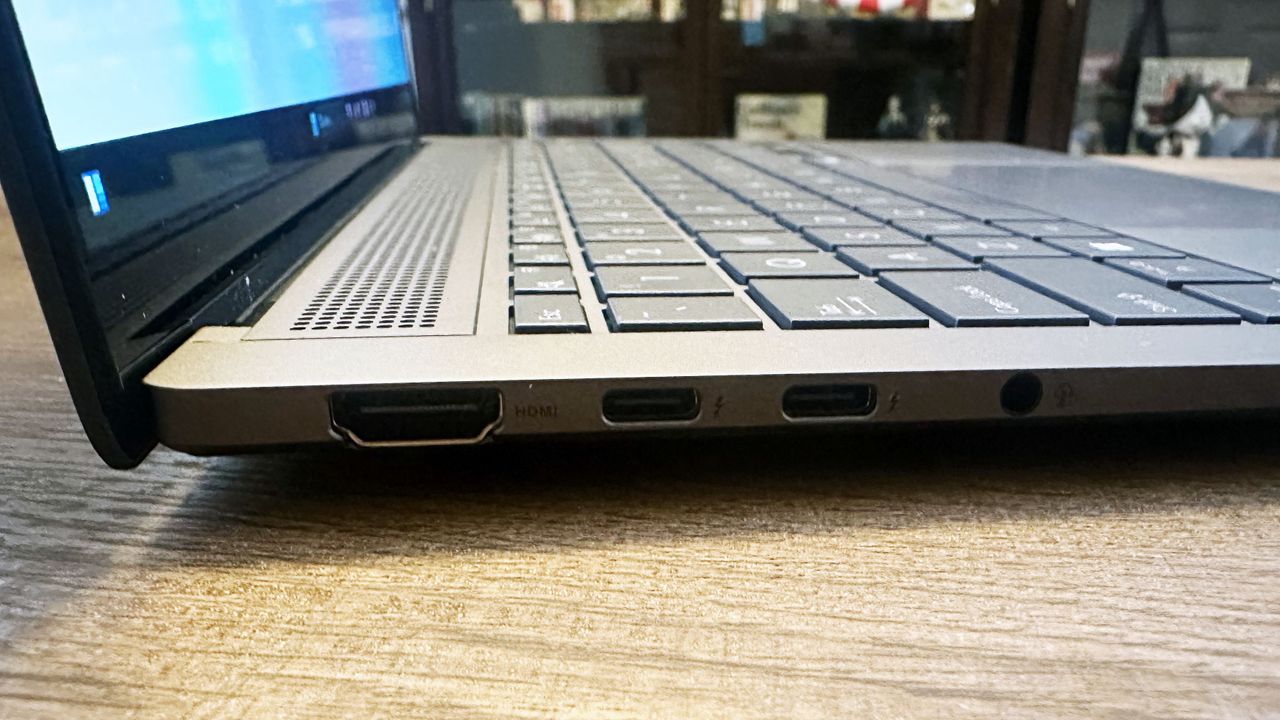 Asus Zenbook S 14 open on a wooden desk showing the ports on its left side.