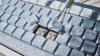 The NuPhy Nos75 mechanical keyboard on a stone surface with a blue background