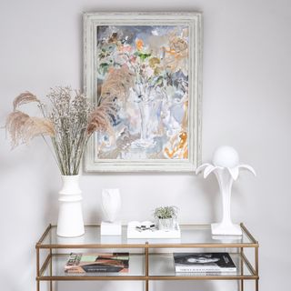Gold rimmed table with white decorative vases, hanging wall art