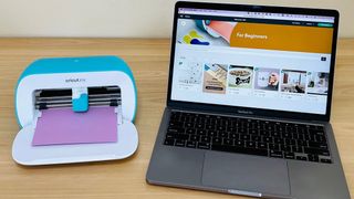 A Cricut Joy sitting next to a laptop on a desk