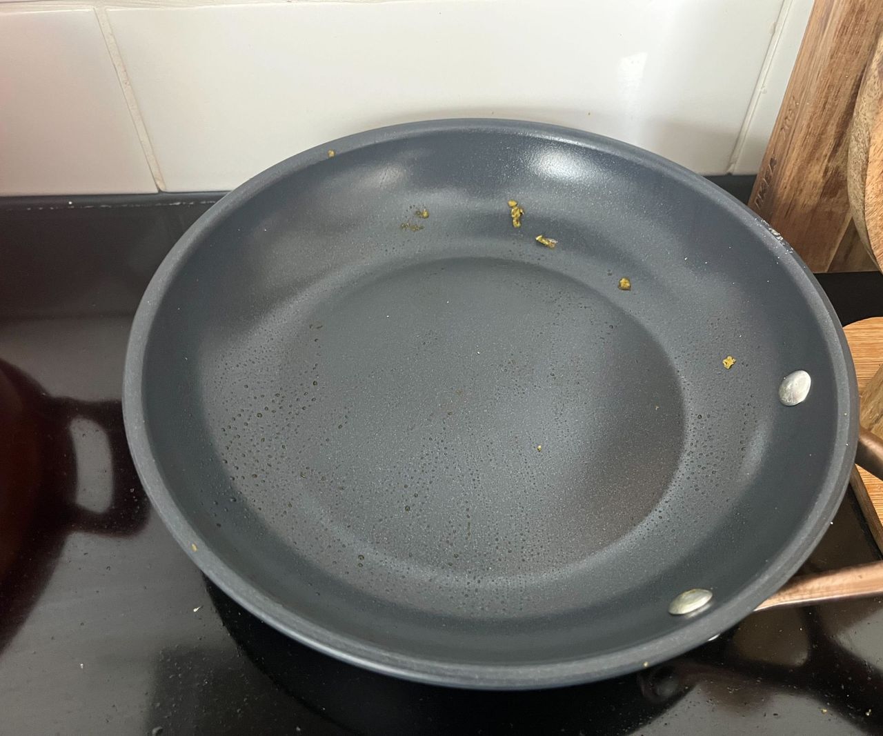 Remnants of green pesto in a small blue ceramic frying pan.