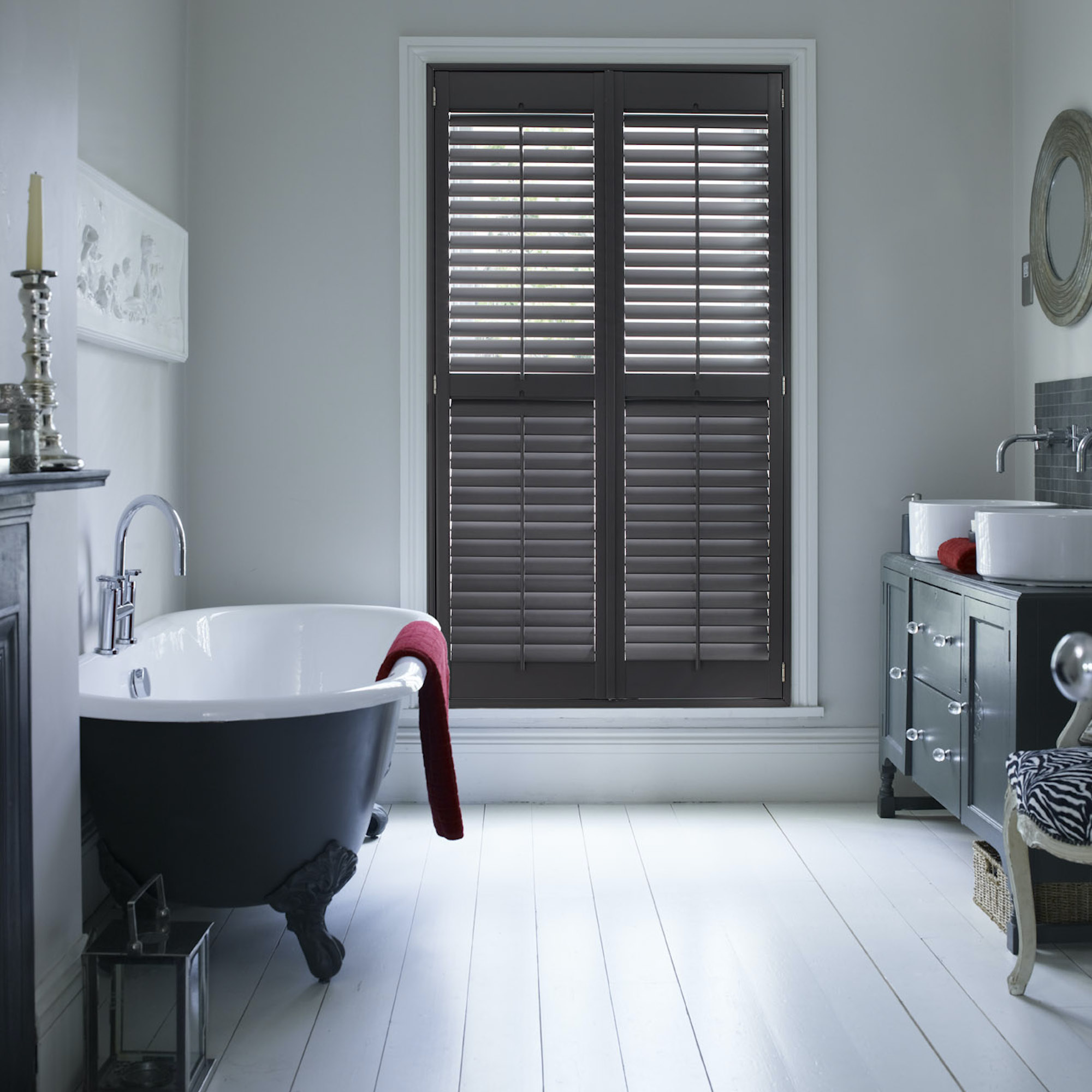 dark painted shutters in white bathroom with roll top bath and painted wooden floors
